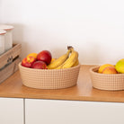 Fruit bowls with woven texture apples and bananas on a wooden surface